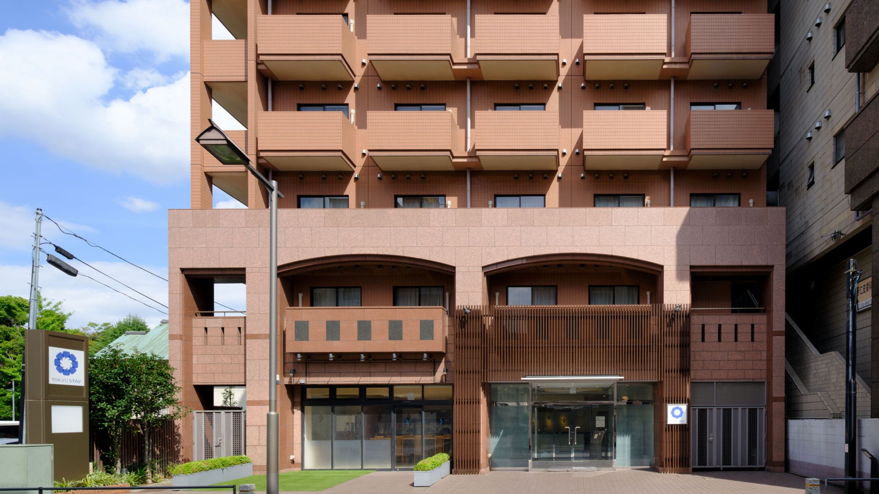 Een meerhoog gebouw met een modern architectonisch ontwerp, met een centrale ingang met glazen deuren en een houten gevel.