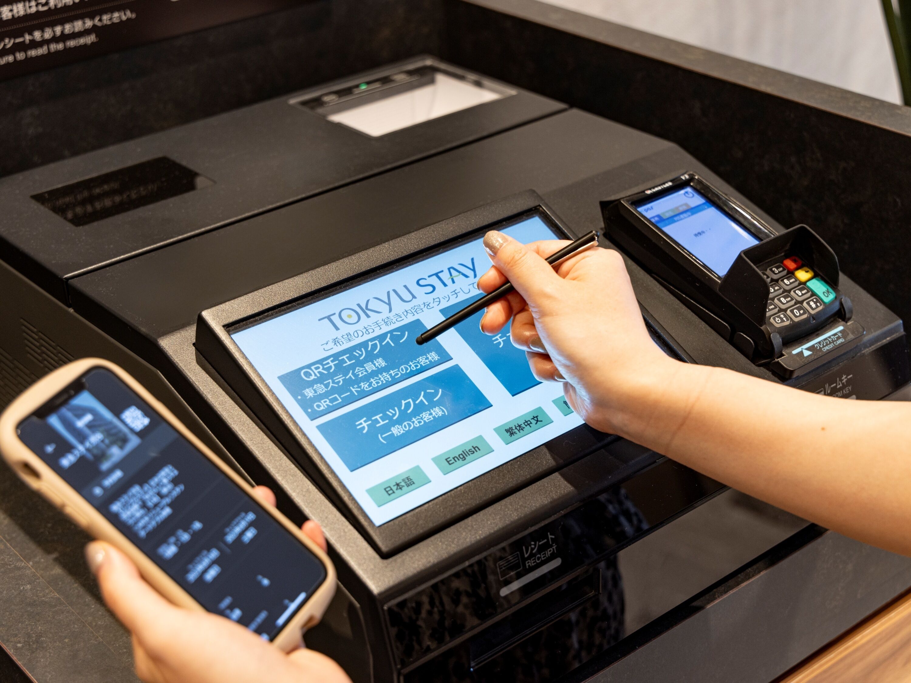 Un kiosque numérique doté d’une interface tactile pour l’enregistrement des clients à l’hôtel, affichant les options de paiement par code QR et par carte de crédit.
