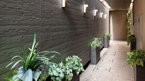 A corridor with a dark wooden wall, potted plants, and a tiled floor. - Tokyu Stay Monzen Nakacho Tokyo (Tokyo)