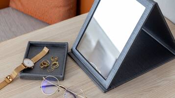 Una cajita de joyería con espejo, que contiene un reloj, anillos y gafas.