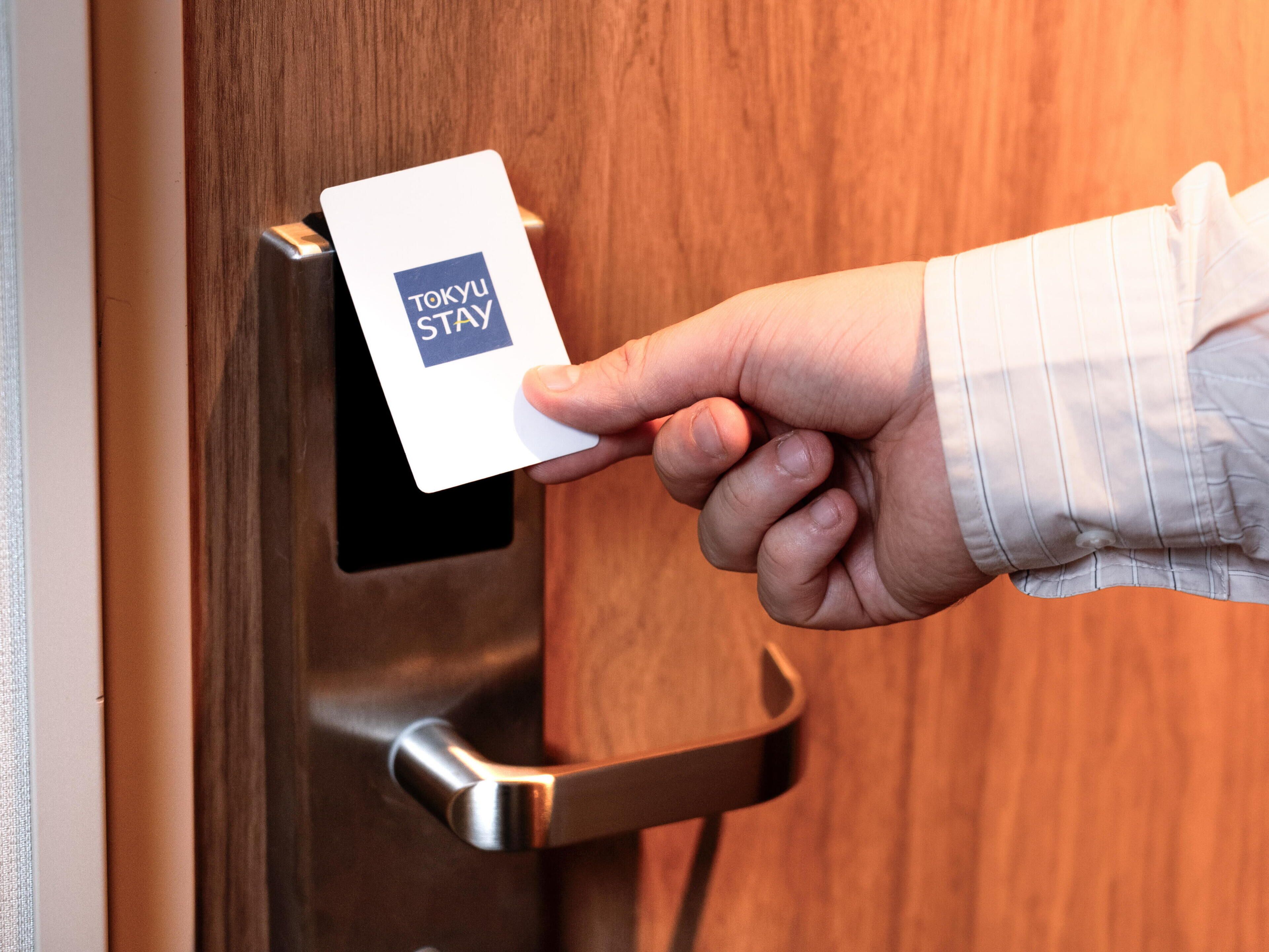A hand inserting a Tokyo Stay card into a hotel door lock.