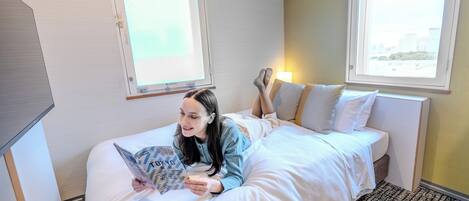 Una habitación de hotel con una cama, una ventana y una lámpara.