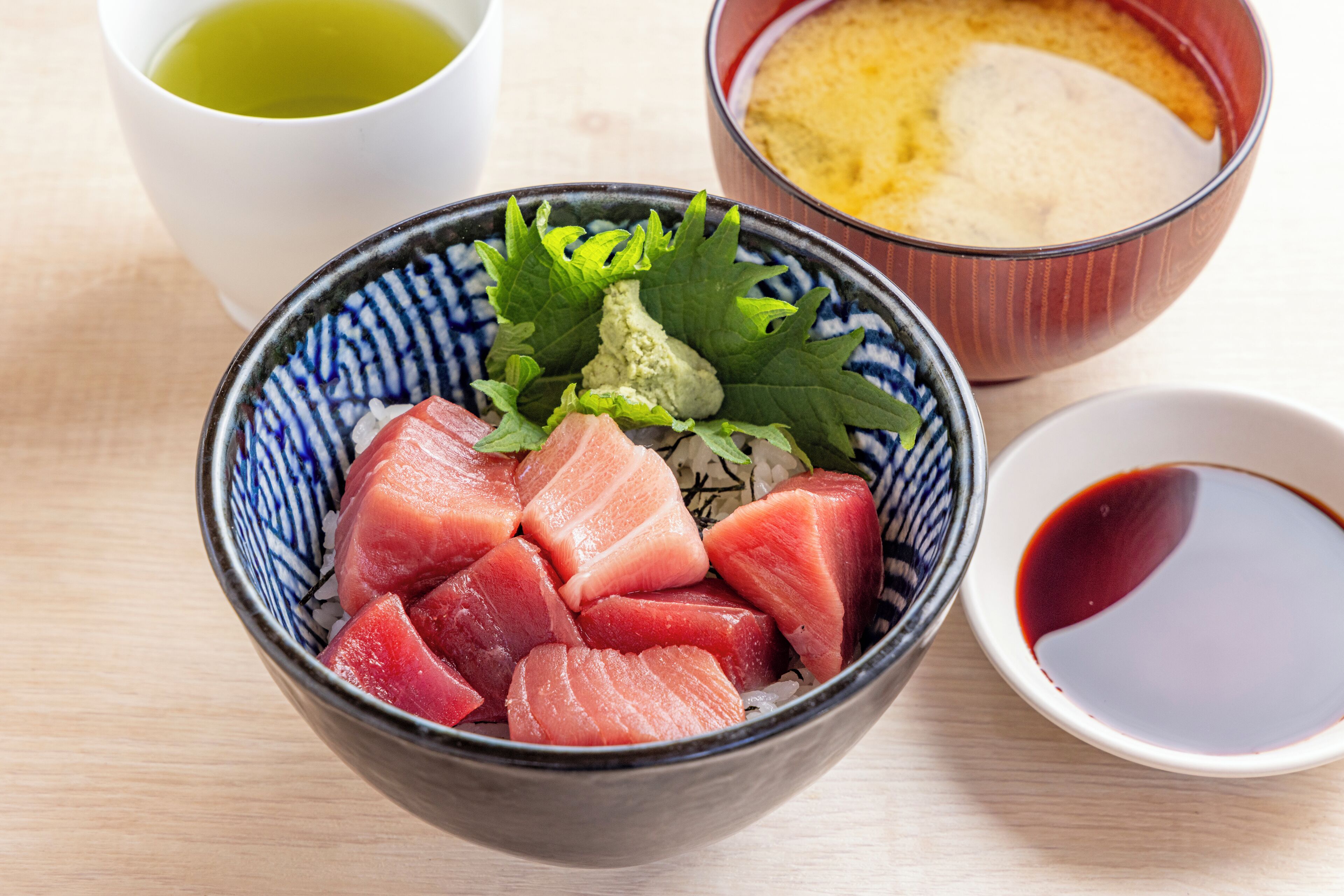 A bowl of sashimi with wasabi, pickled ginger, and a small bowl of soy sauce.