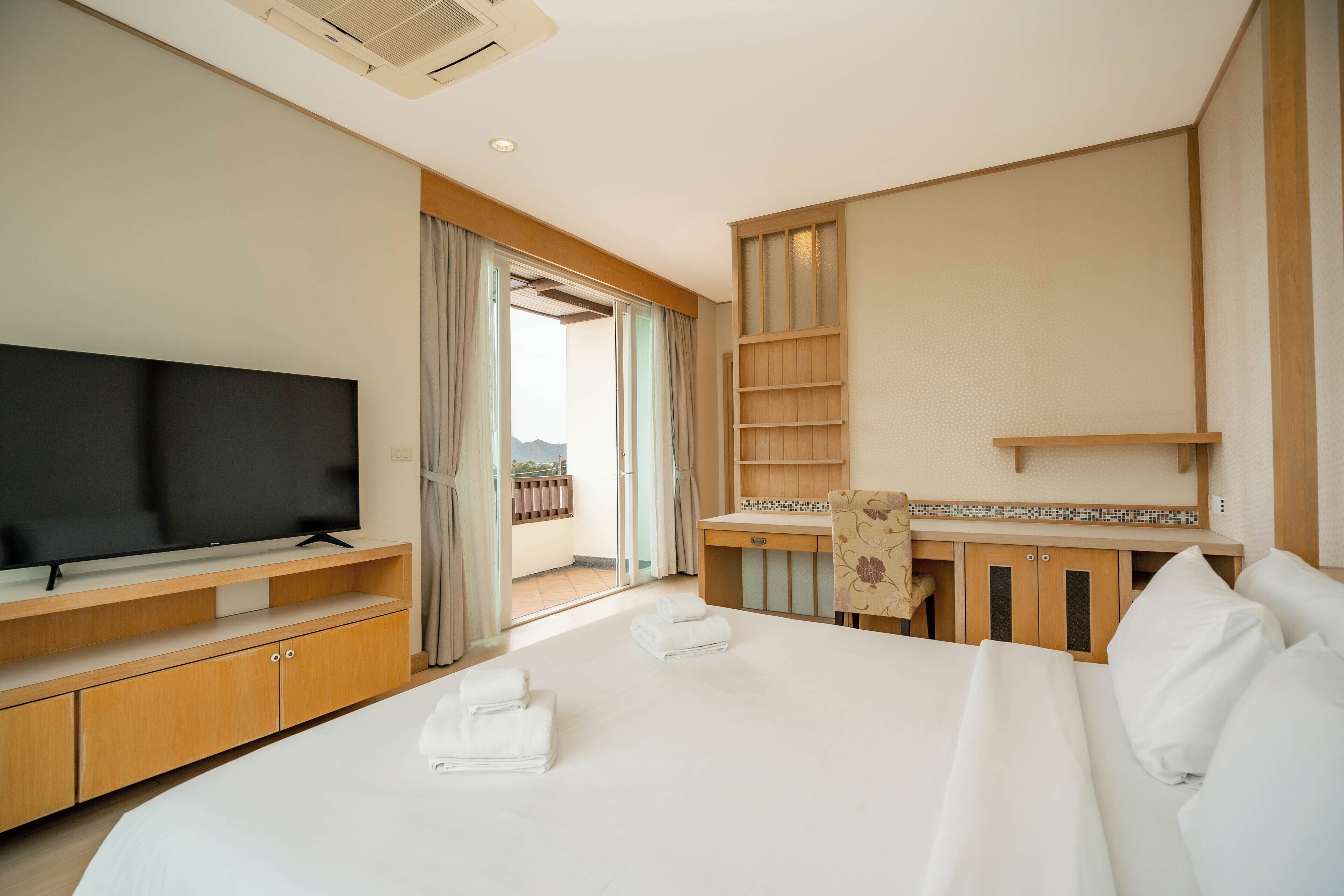 Ein Hotelzimmer mit Bett, Fernseher, Schreibtisch und Badebereich.