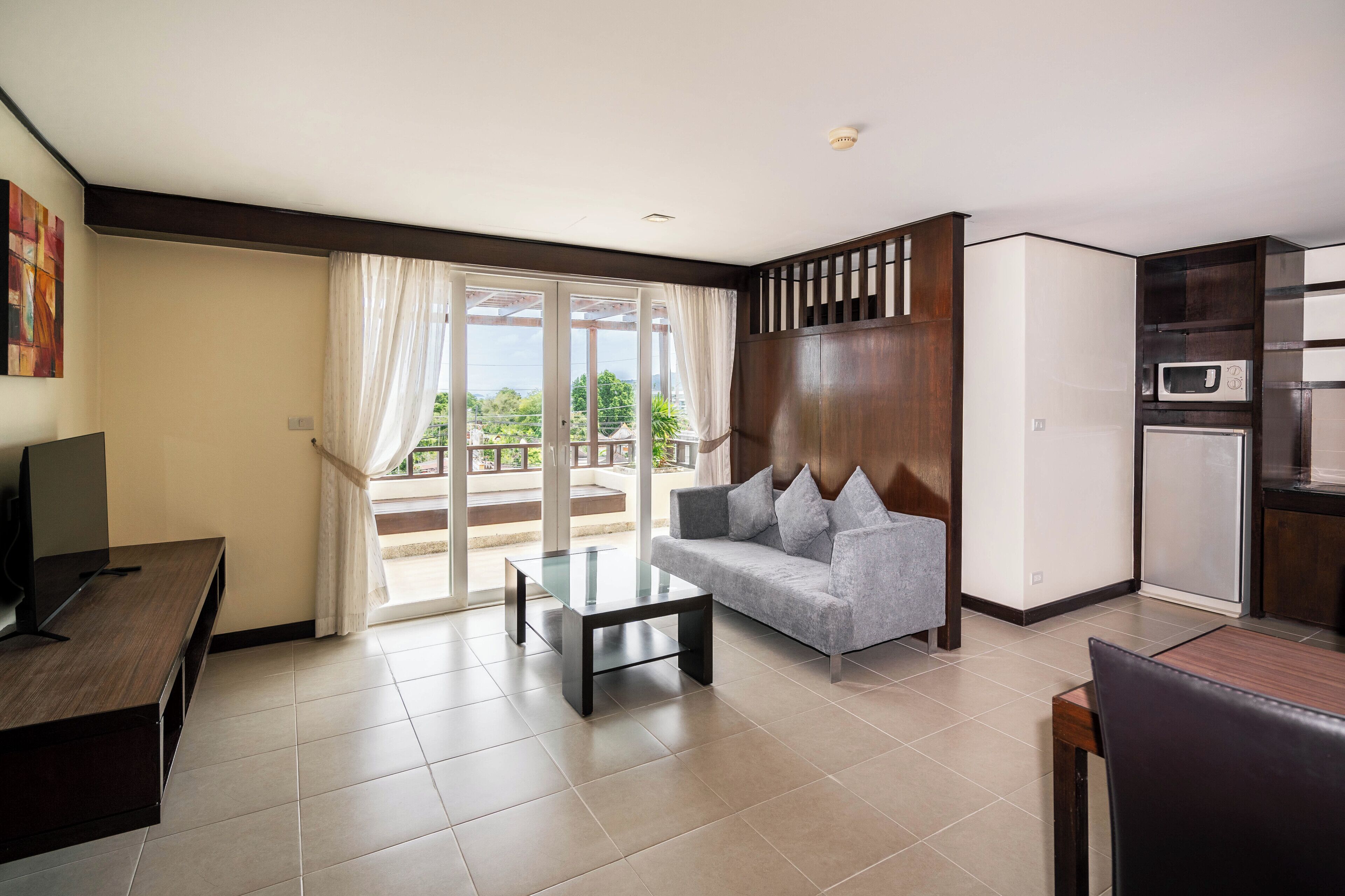 A modern living room with a sofa, coffee table, TV, and kitchen area with appliances.