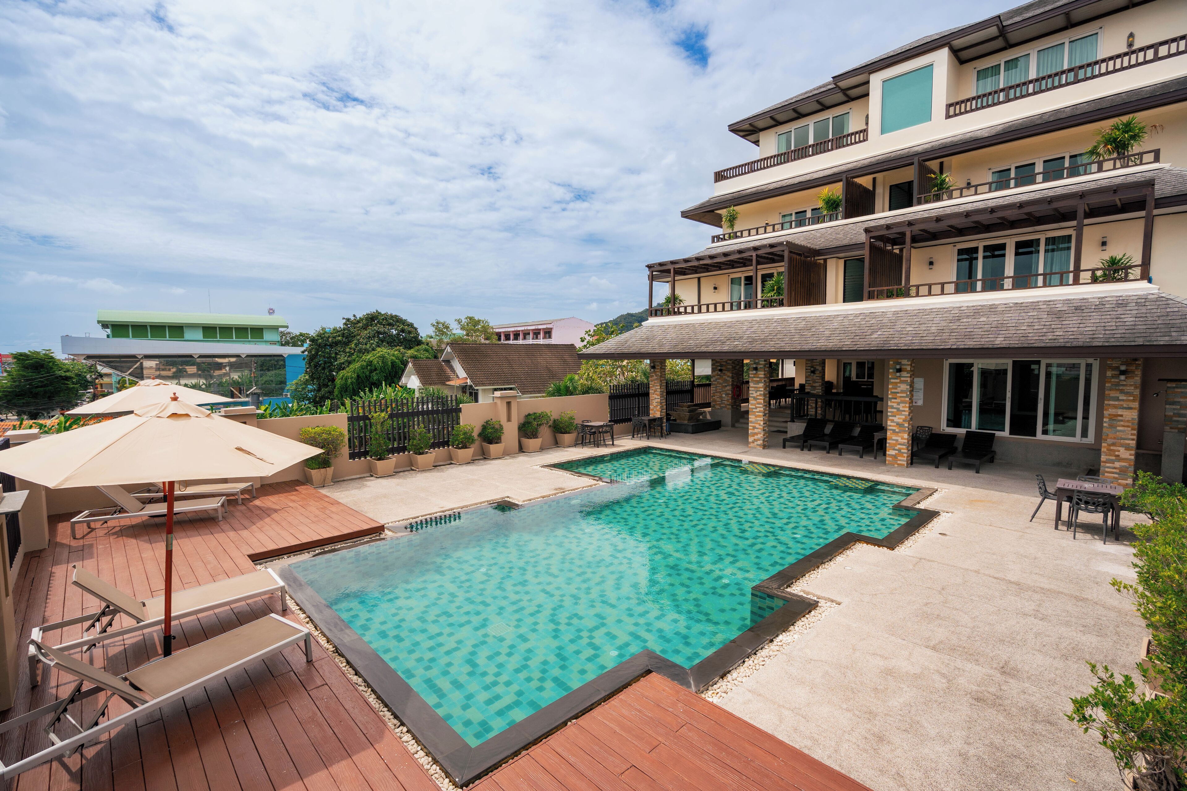 A swimming pool with a wooden deck, lounge chairs, and umbrellas.