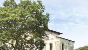 A building with a classical architectural style, featuring a central section with columns and a covered walkway.