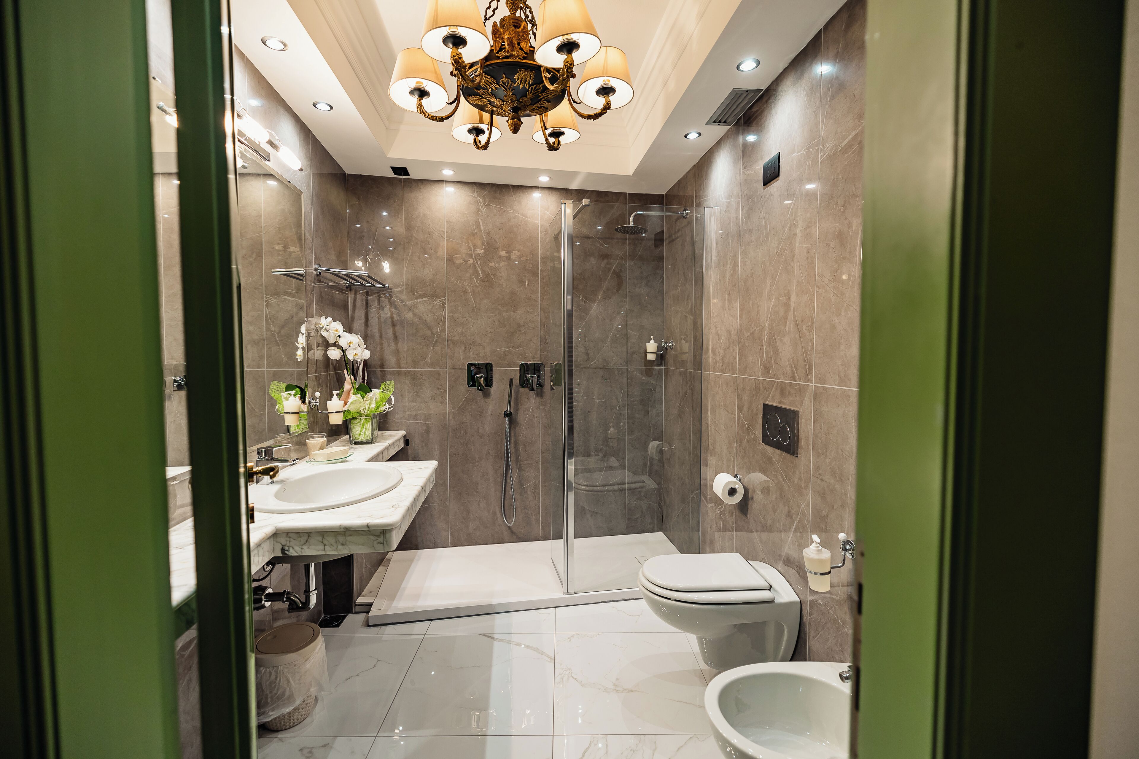 A modern bathroom with a glass-enclosed shower, a white toilet, and a marble sink.