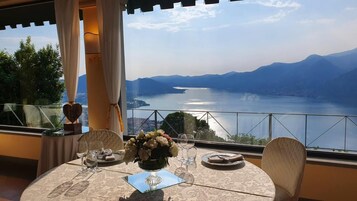 Une table dressée pour deux personnes, avec vue sur un lac et des montagnes.