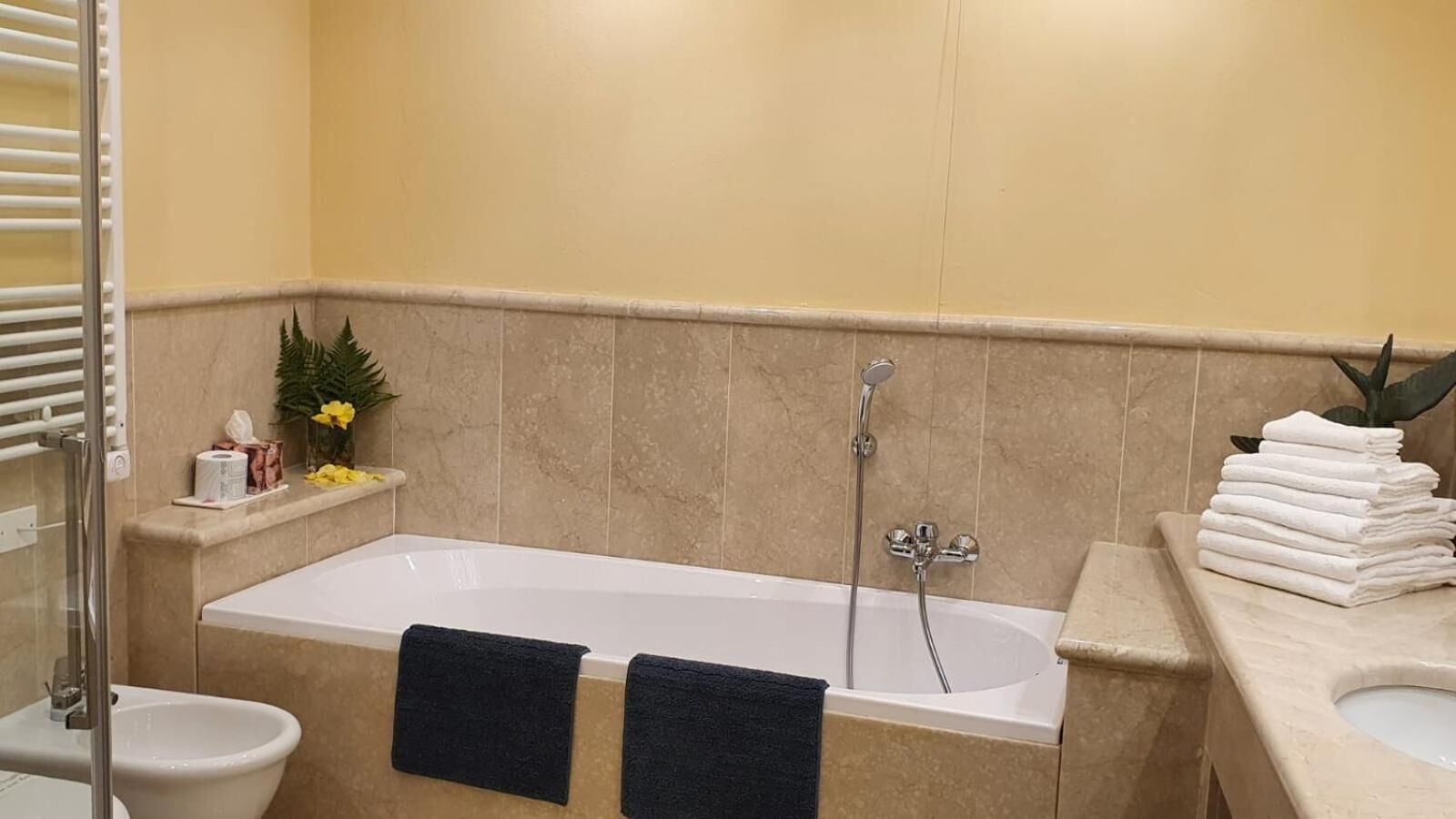 A bathroom with a bathtub, a toilet, and a sink. There are towels and toiletries on the counter.