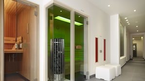 A modern hotel lobby with a wooden sauna, a glass elevator, and a seating area with white stools.