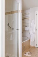 Ein Badezimmer mit Duschkabine aus Glas, einer Badewanne und einem weißen Handtuchhalter.