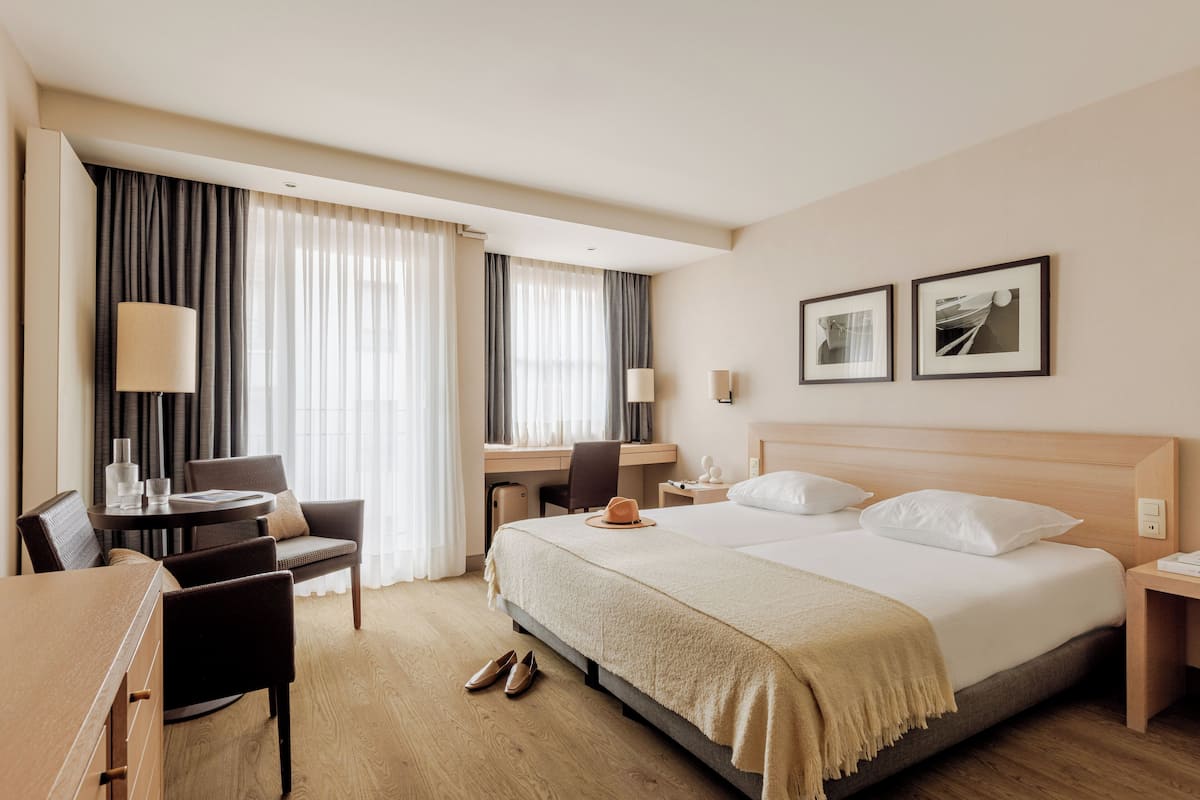 A hotel room with a bed, desk, chair, and a dining table.