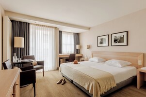 A hotel room with a bed, desk, chair, and a dining table.