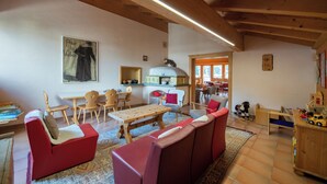 Un salon chaleureux avec des canapés rouges, une table en bois et un coin cuisine à l’arrière-plan.