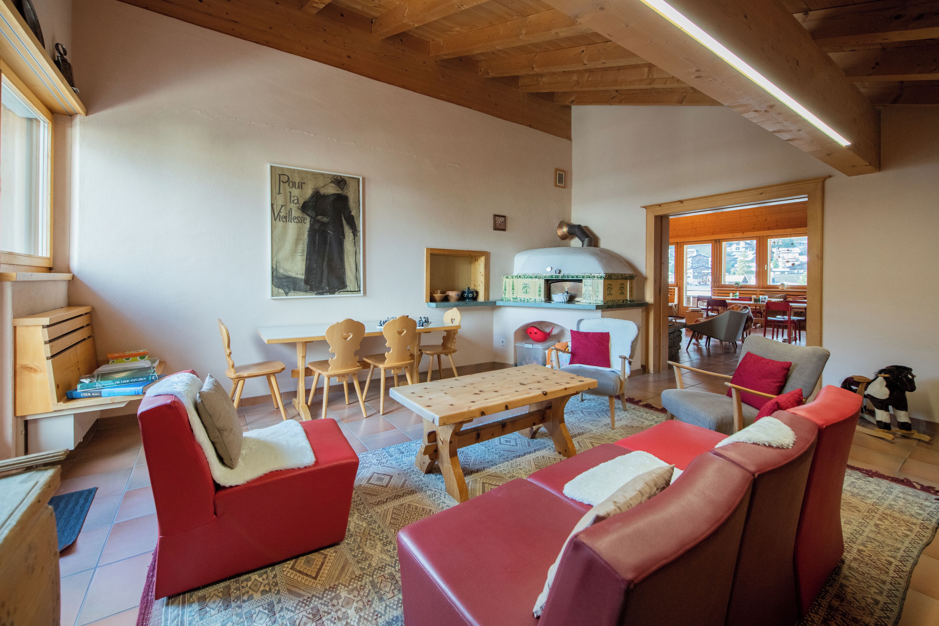 Una sala de estar acogedora con sofás rojos, una mesa de madera y una cocina con horno para pizza.