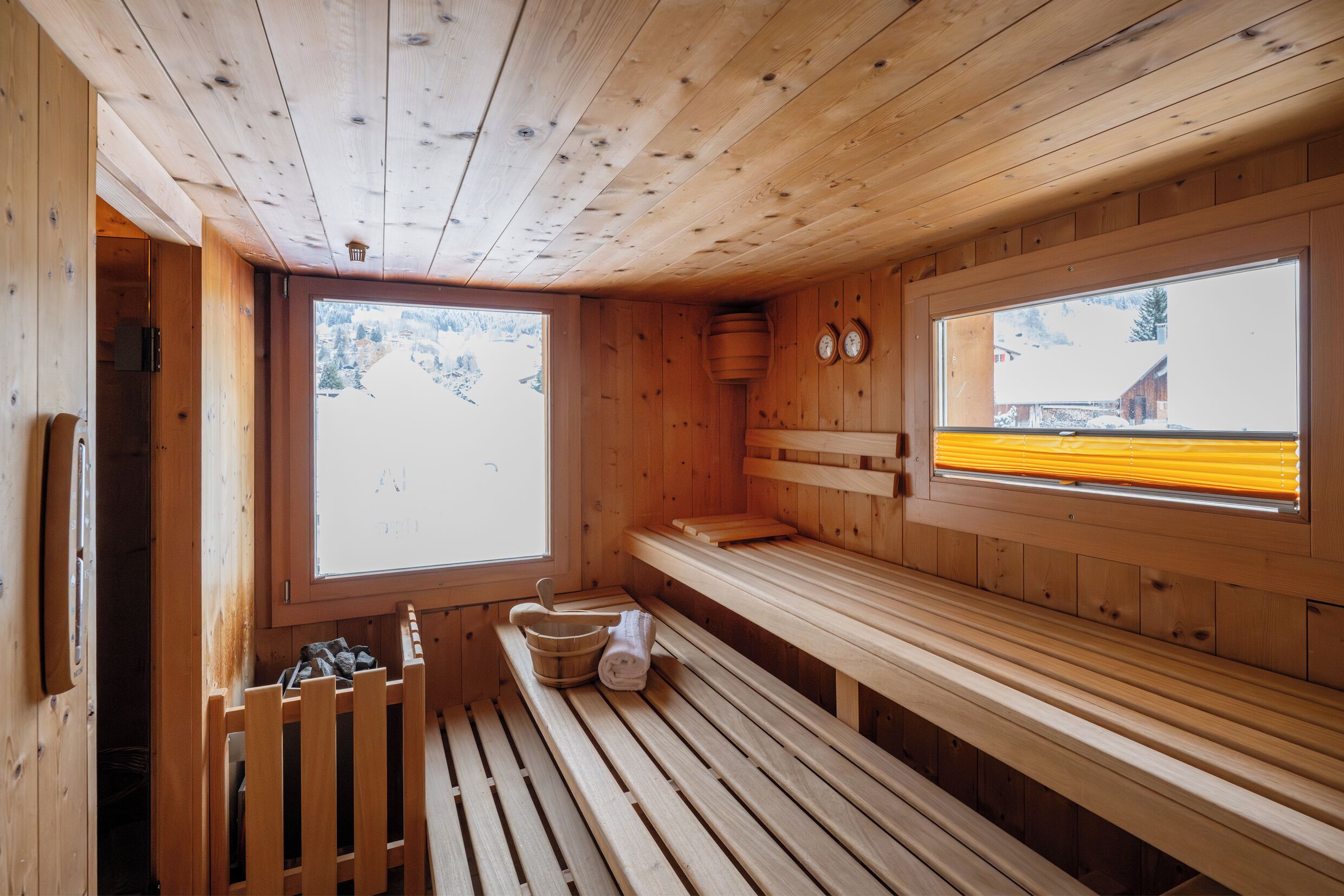 Una sauna de madera con bancos, una ventana y vistas a un paisaje nevado.