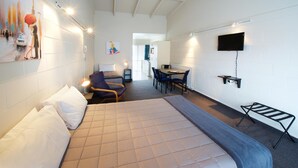 A hotel room with a bed, a desk, a chair, a TV, and a painting on the wall. - Ambassador Thermal Motel (Rotorua)