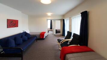 A modern hotel room with a sofa, a chair, a bed, and a painting on the wall.