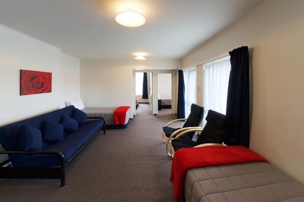 Una habitación de hotel moderna con sofá, una silla, una cama y un cuadro en la pared.
