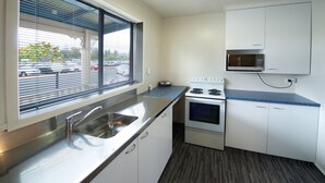 A compact kitchen with a stainless steel sink, a built-in microwave, and a stove. - Ambassador Thermal Motel (Rotorua)