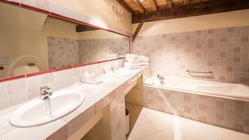 A bathroom with a sink, mirror, and bathtub.