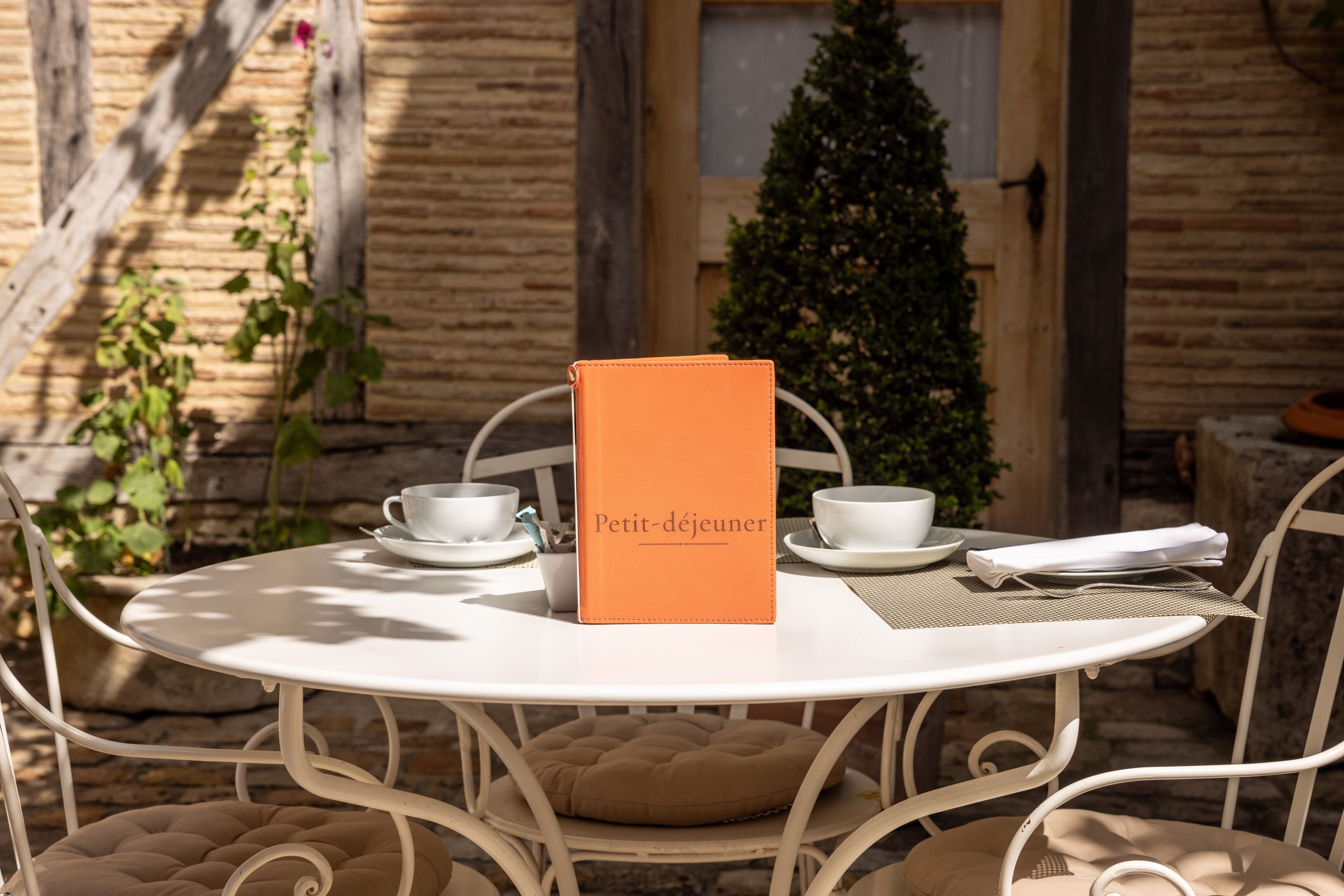 A round white table with a menu, two white cups, and a folded napkin.