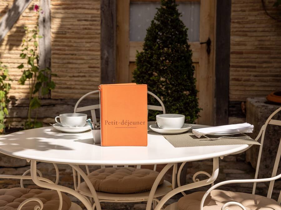 A round white table with a menu, two white cups, and a folded napkin.