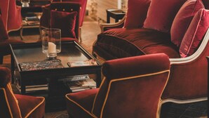 A cozy room with red upholstered furniture, a brick wall, and a table with a candle.