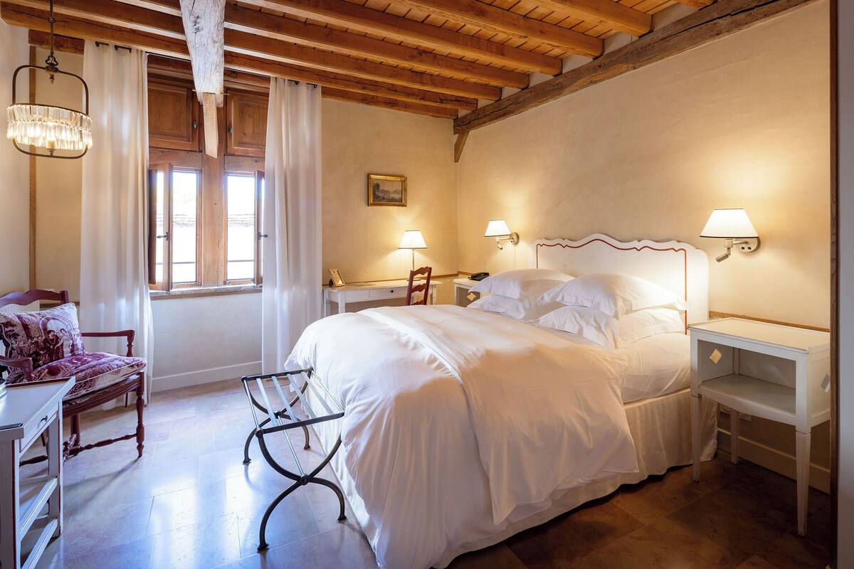 A bedroom with a large bed, bedside tables, a chair, and a desk.