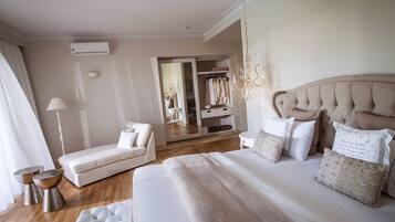 A bedroom with a large bed, a bedside table, a chair, a wardrobe, and a chandelier.