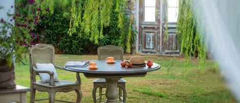 A round table with two chairs, a hat, and a fruit on it.