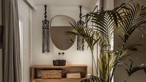 A bathroom with a wooden vanity, a large mirror, and a potted plant. - SunVillage Boutique Hotel (Hersonissos)