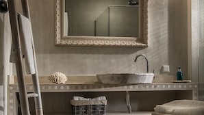A bathroom with a large mirror, a vessel sink, a towel rack, a wooden ladder, and a woven rug. - SunVillage Boutique Hotel (Hersonissos)