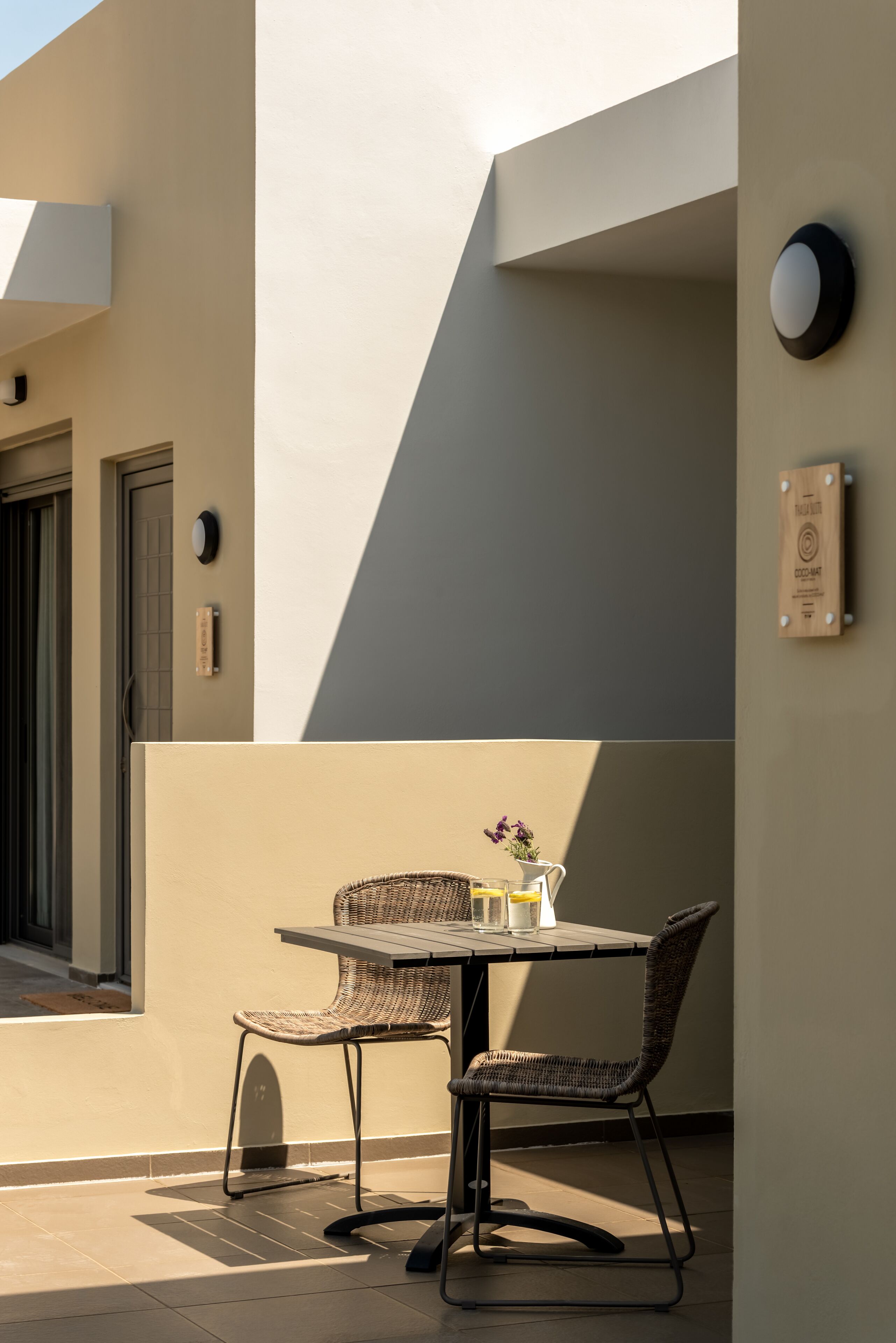Un'area salotto esterna con tavolo e due sedie, una porta e un lampadario a parete.
