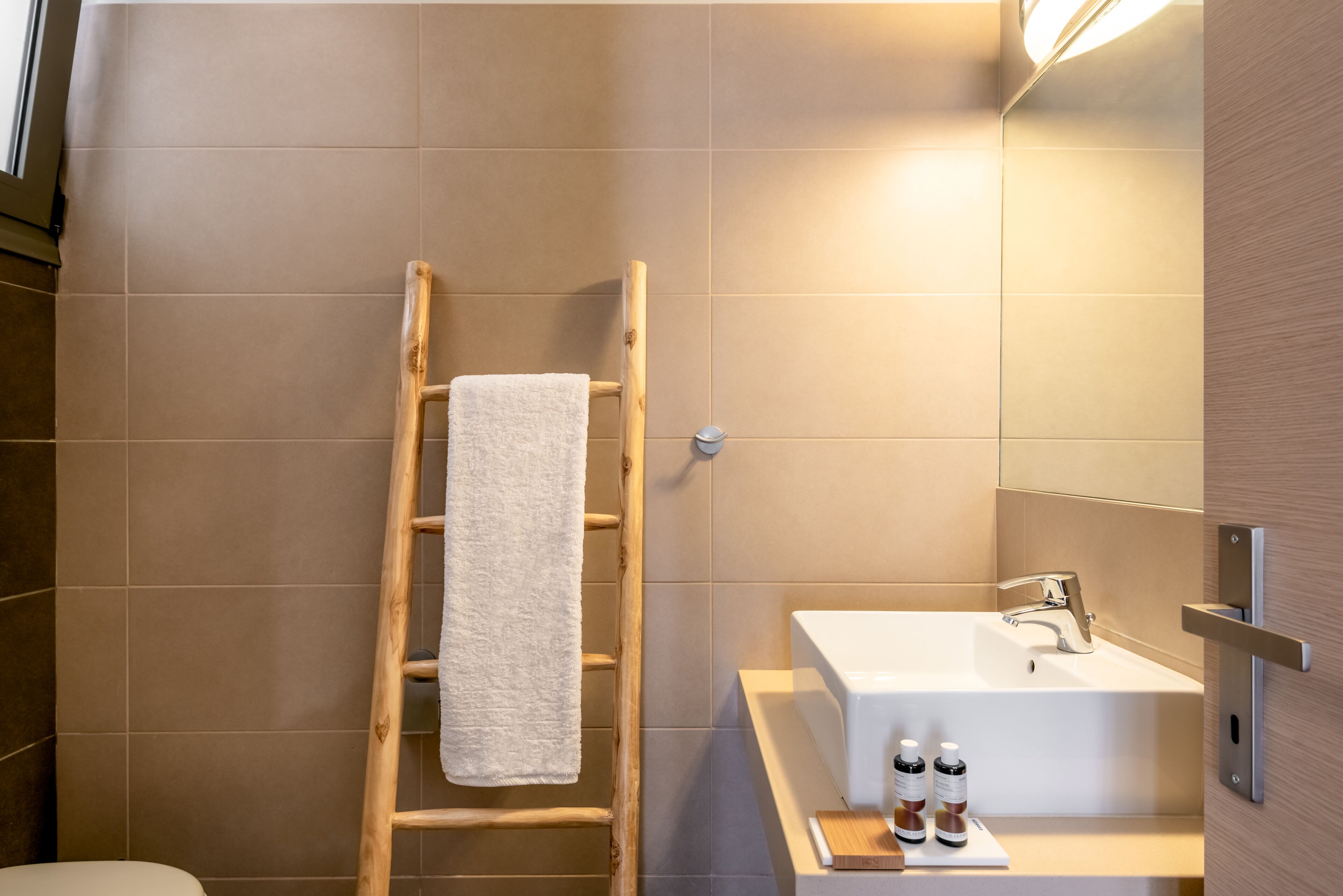 A bathroom with a wooden ladder, a white sink, and a mirror.