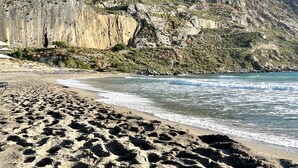 A sandy beach with rocky cliffs in the background. - Plakias Suites (Agios Vasileios)