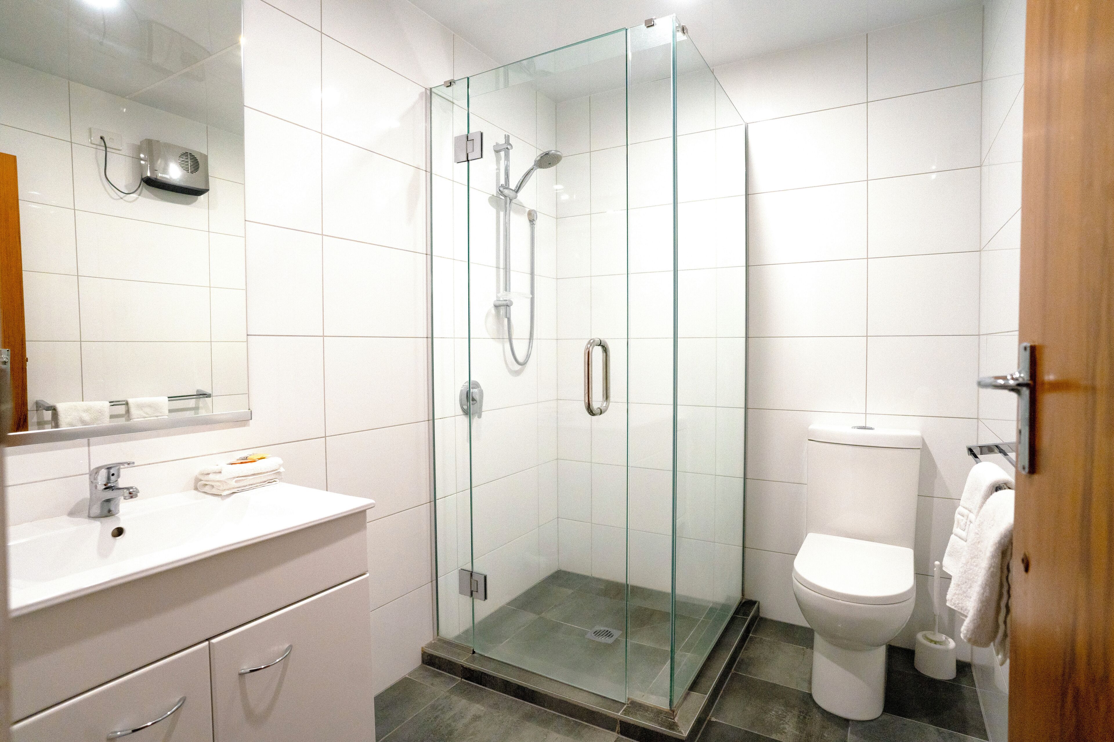 A modern bathroom with a glass-enclosed shower, a white sink with a mirror, and a toilet.