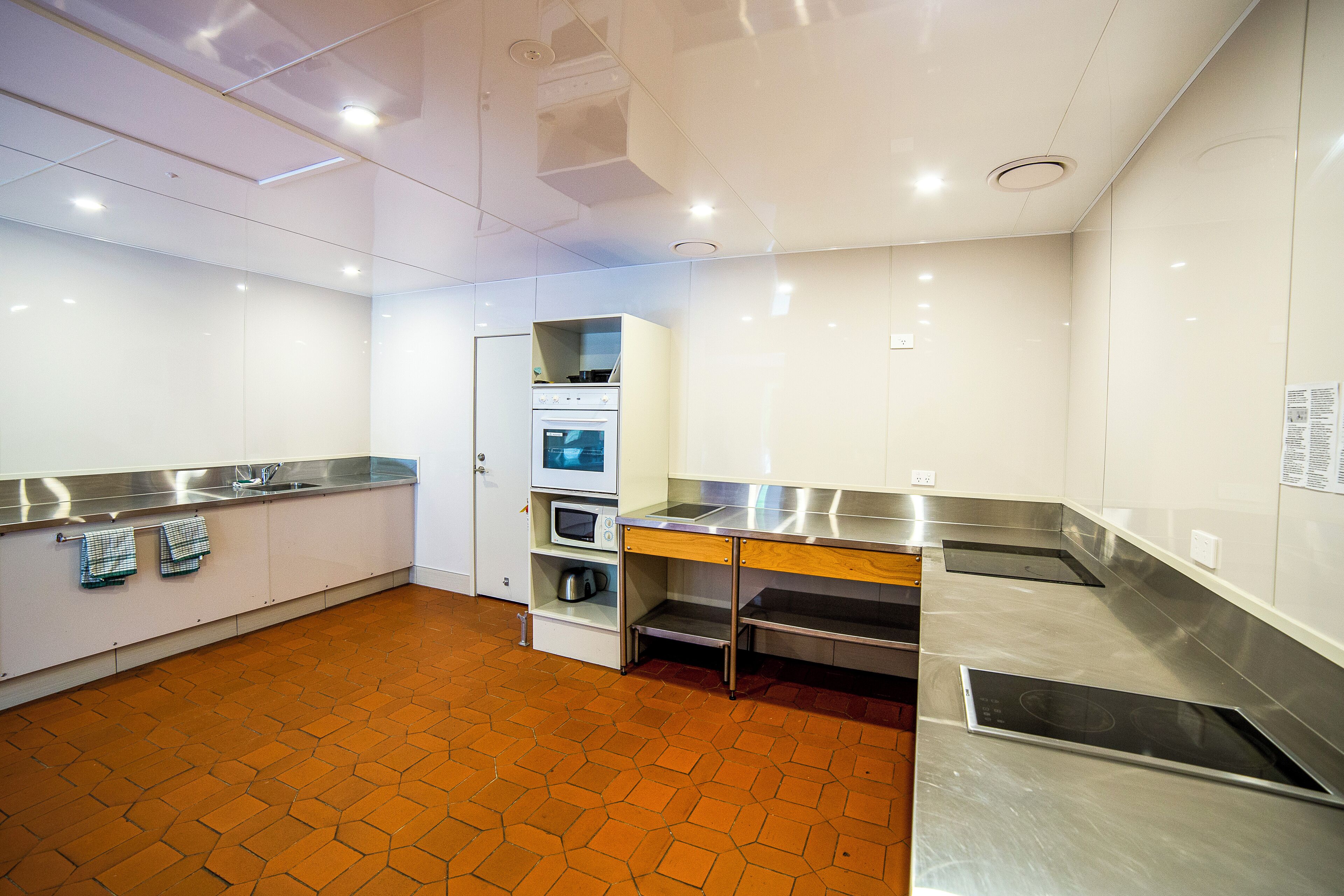 A modern kitchen with stainless steel appliances, a wooden countertop, and a hexagonal floor pattern.