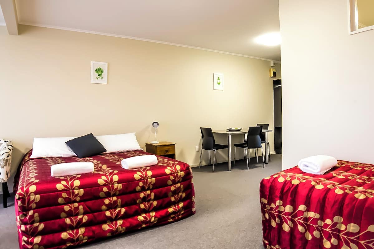 A hotel room with two beds, a desk, and chairs.