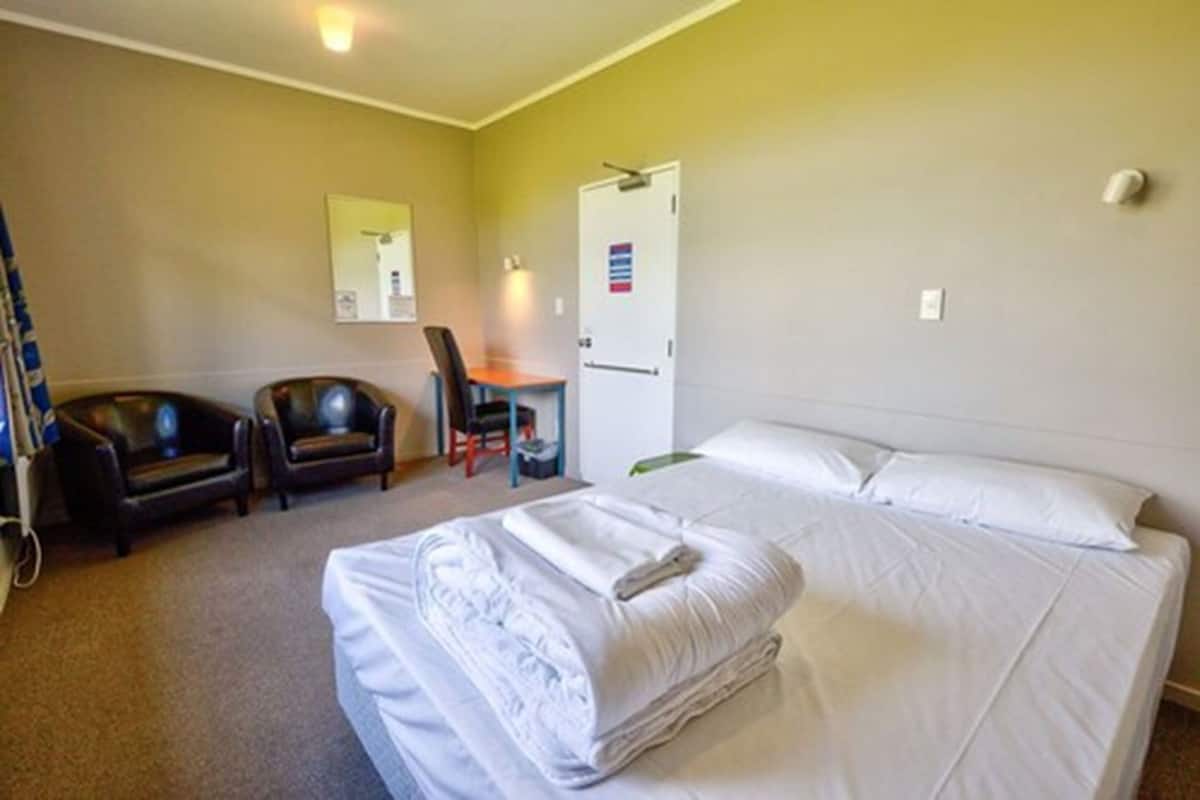 A hotel room with two beds, a desk, a chair, and a couch.