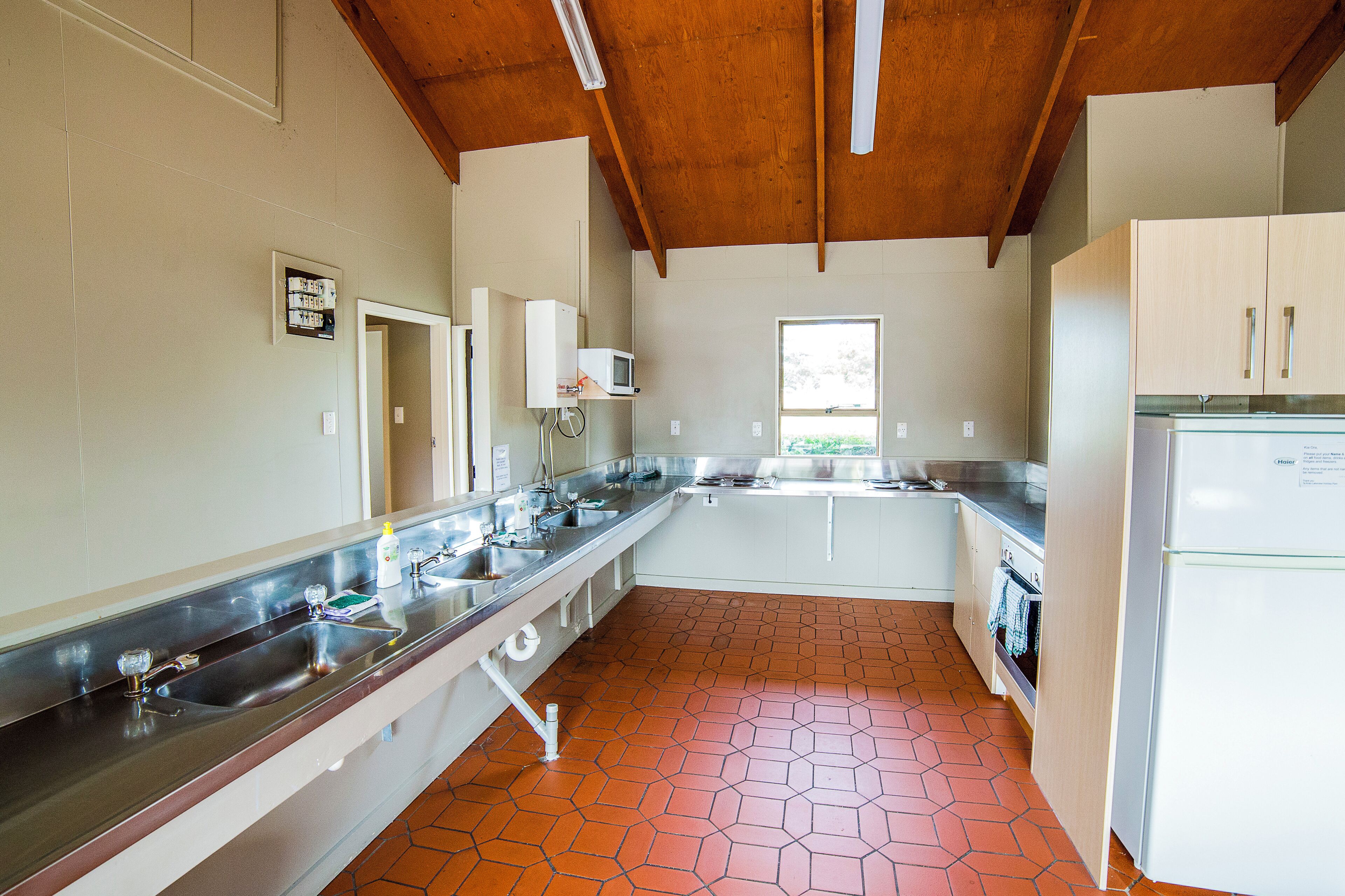 A kitchen with a long countertop, stainless steel sink, and a microwave.