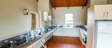 A kitchen with a long countertop, stainless steel sink, and a microwave.