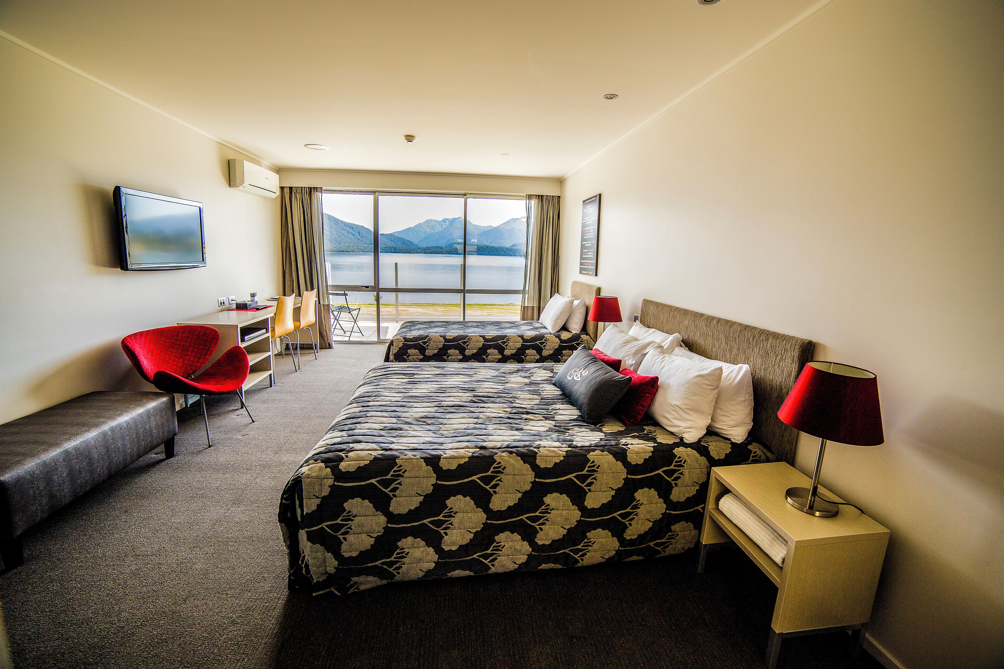 A hotel room with a large bed, a desk, a chair, and a TV.
