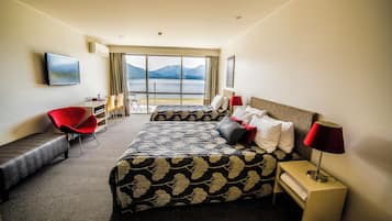 A hotel room with a large bed, a desk, a chair, and a TV.