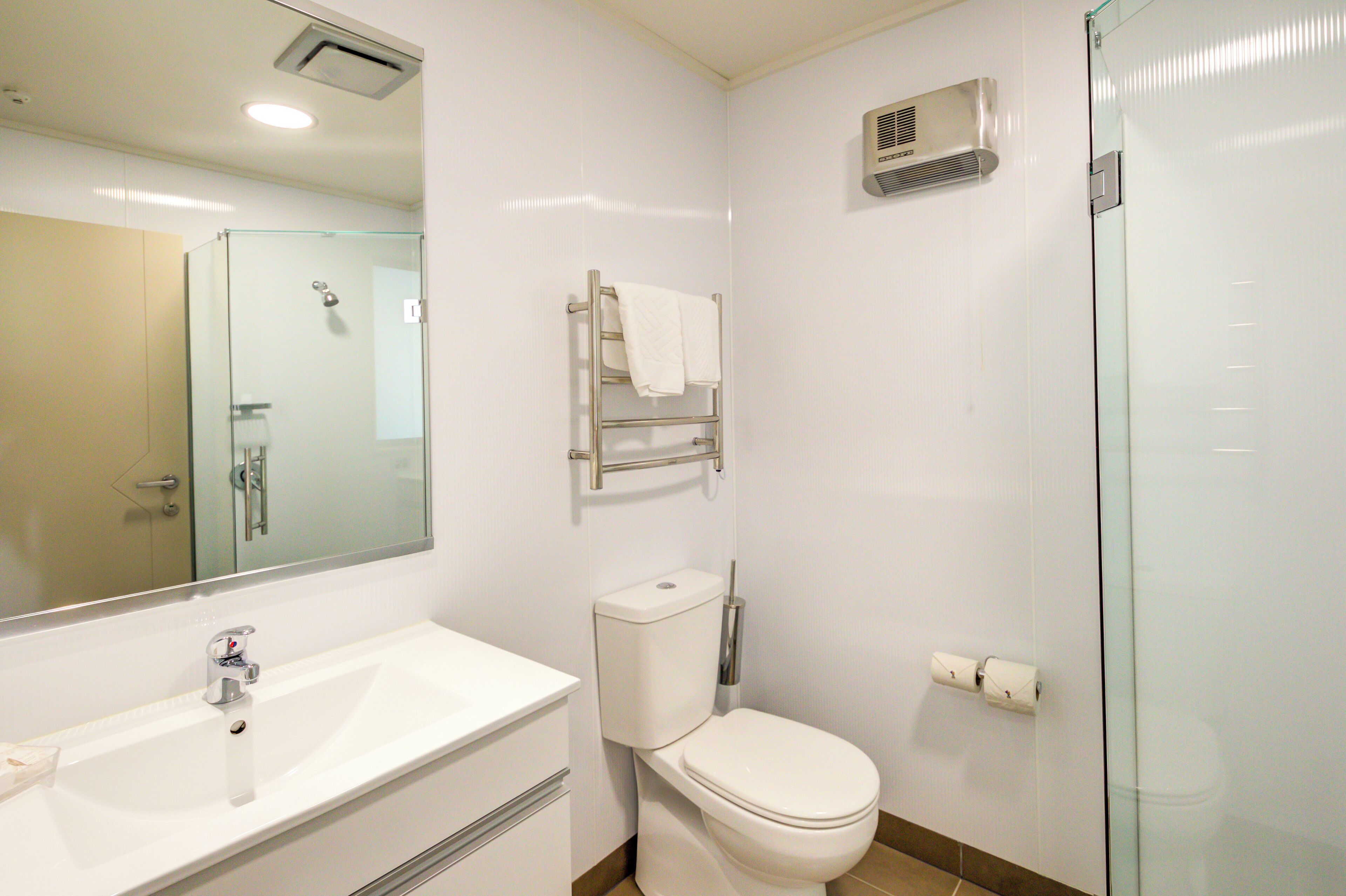 A modern bathroom with a glass shower enclosure, a white sink, and a toilet.