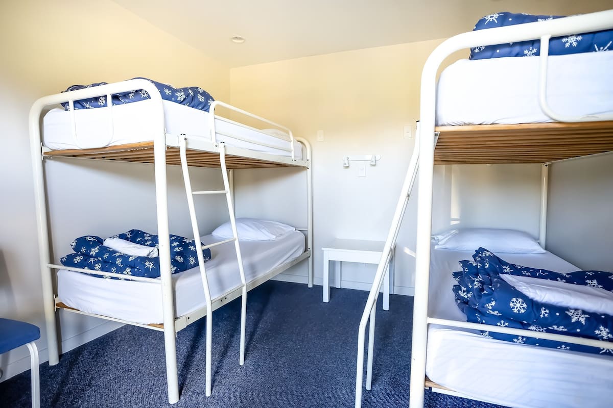 A room with two bunk beds, a small table, and a blue carpet.