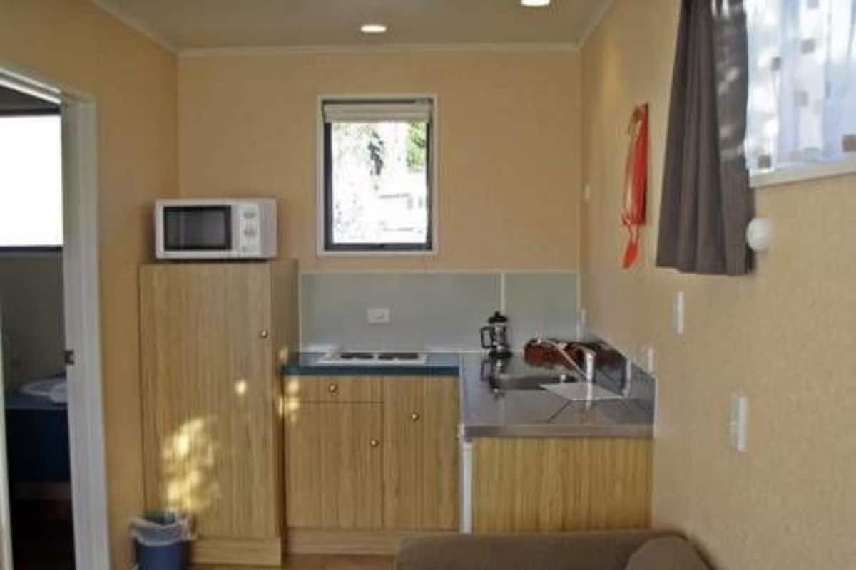 A compact kitchen with a microwave, a sink, and a window.