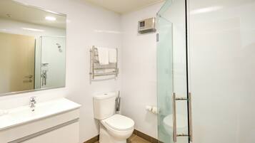 Un bany modern amb un lavabo blanc, vàter i cabina de dutxa de vidre.