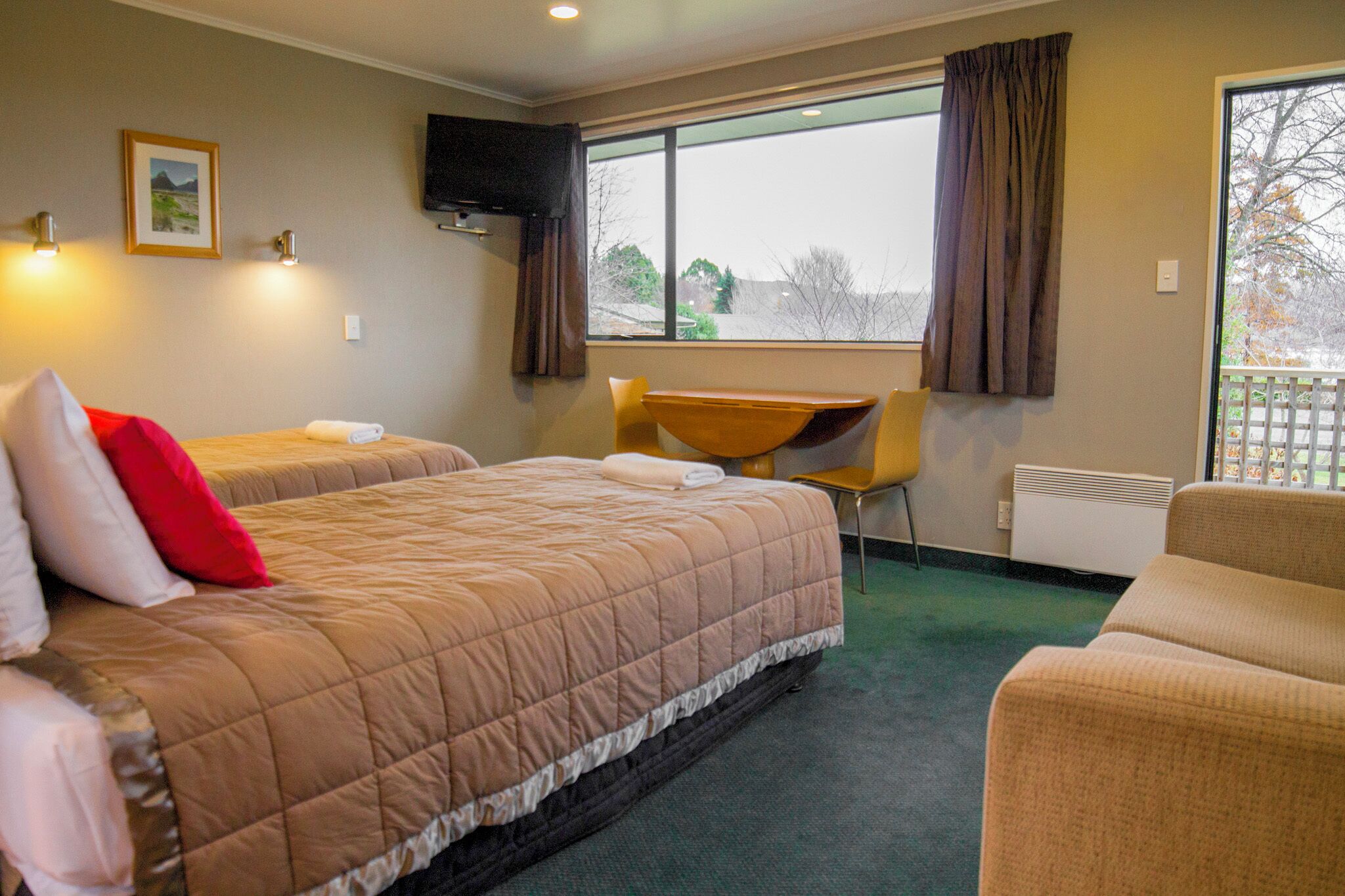 A hotel room with two beds, a desk, and a chair.
